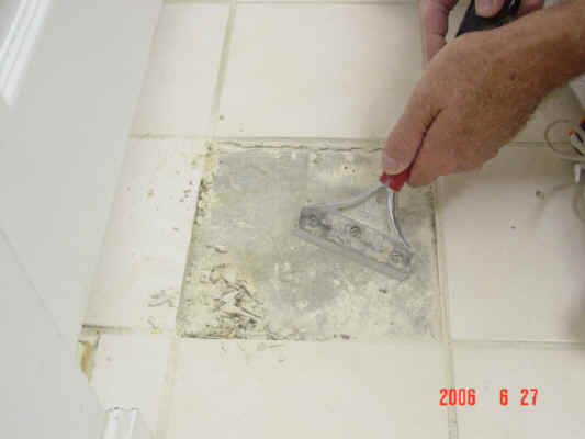 Scraping off tile adhesive from floor